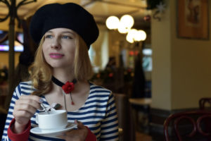 A girl with French hat drinking coffee