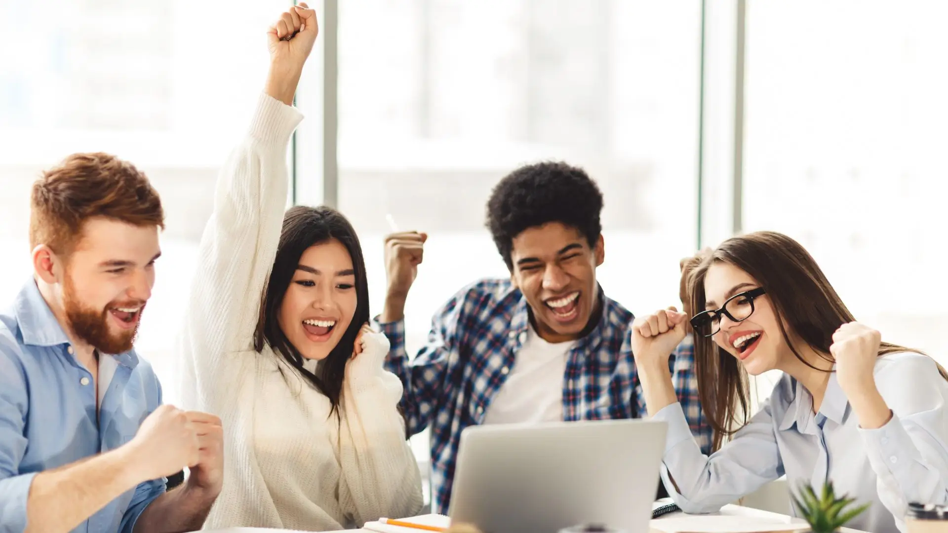Team celebrating success around a laptop.